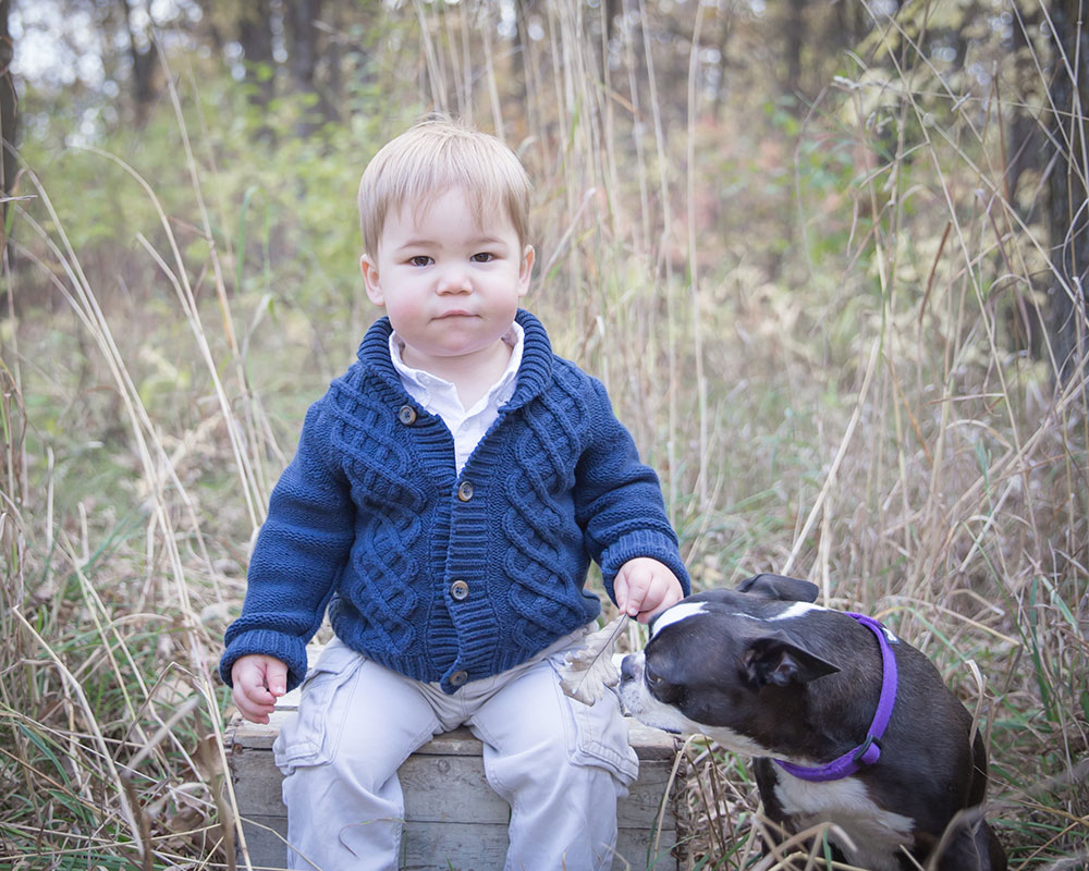 a photo of a little boy sitting on a crate with his dog