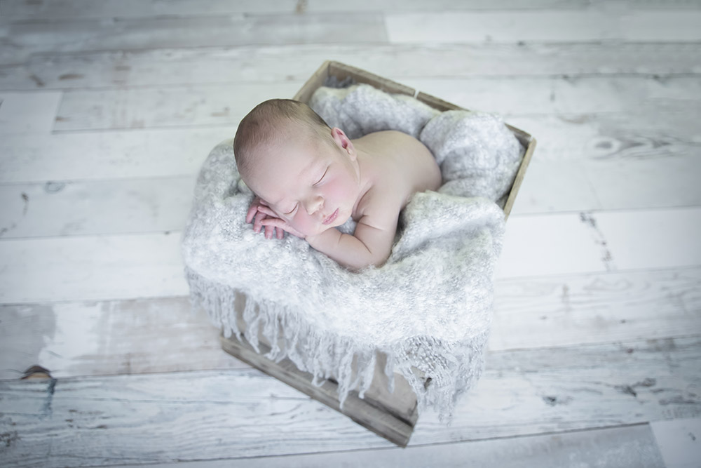 a newborn baby boy sleeping in an old wooden crate