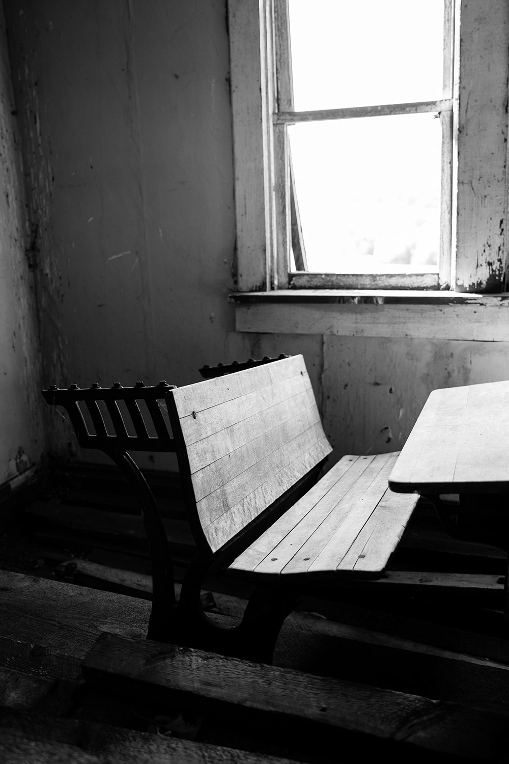 a black and white photo of an old desk in an abandoned home