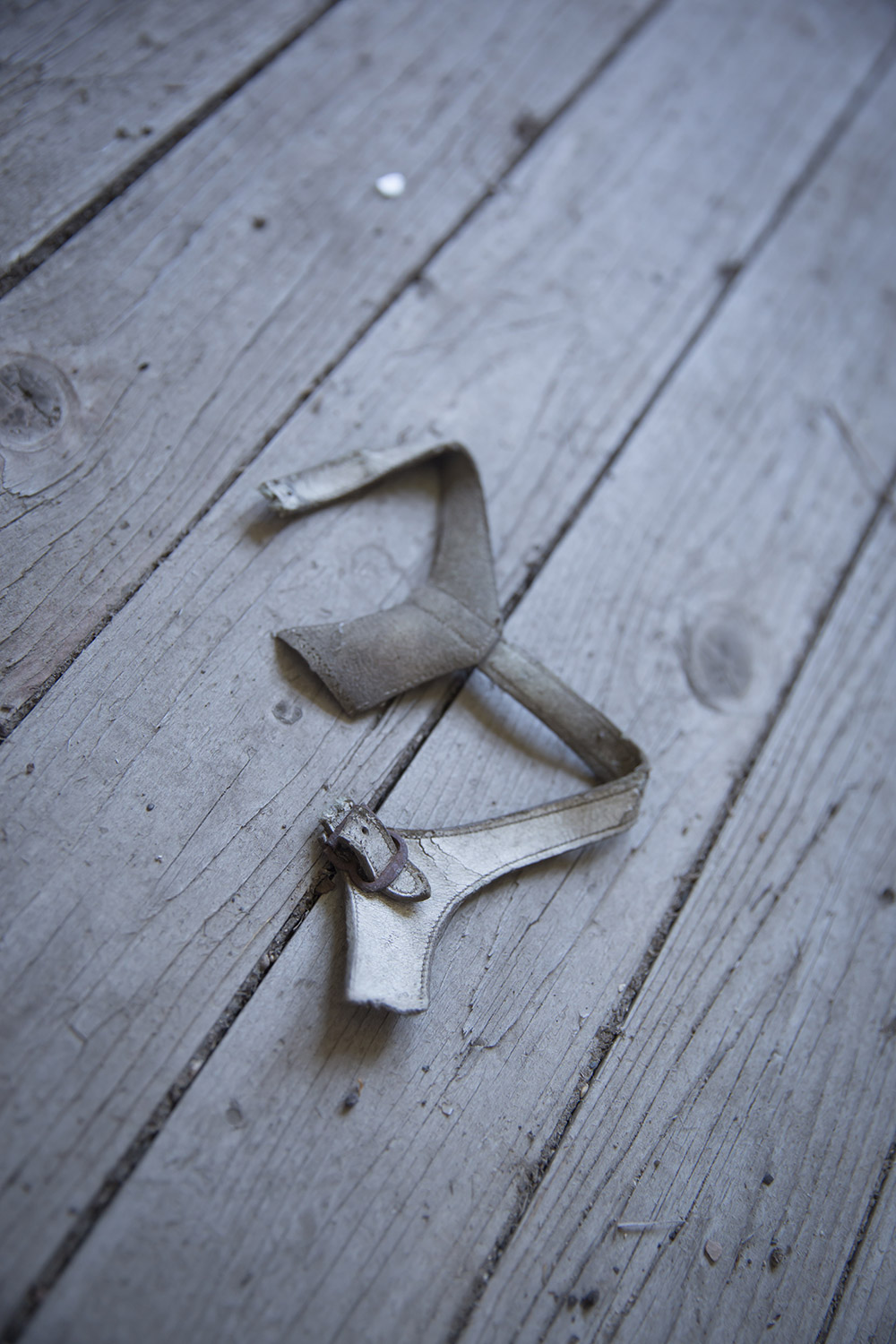 a photo of a sandal strap on a wood floor