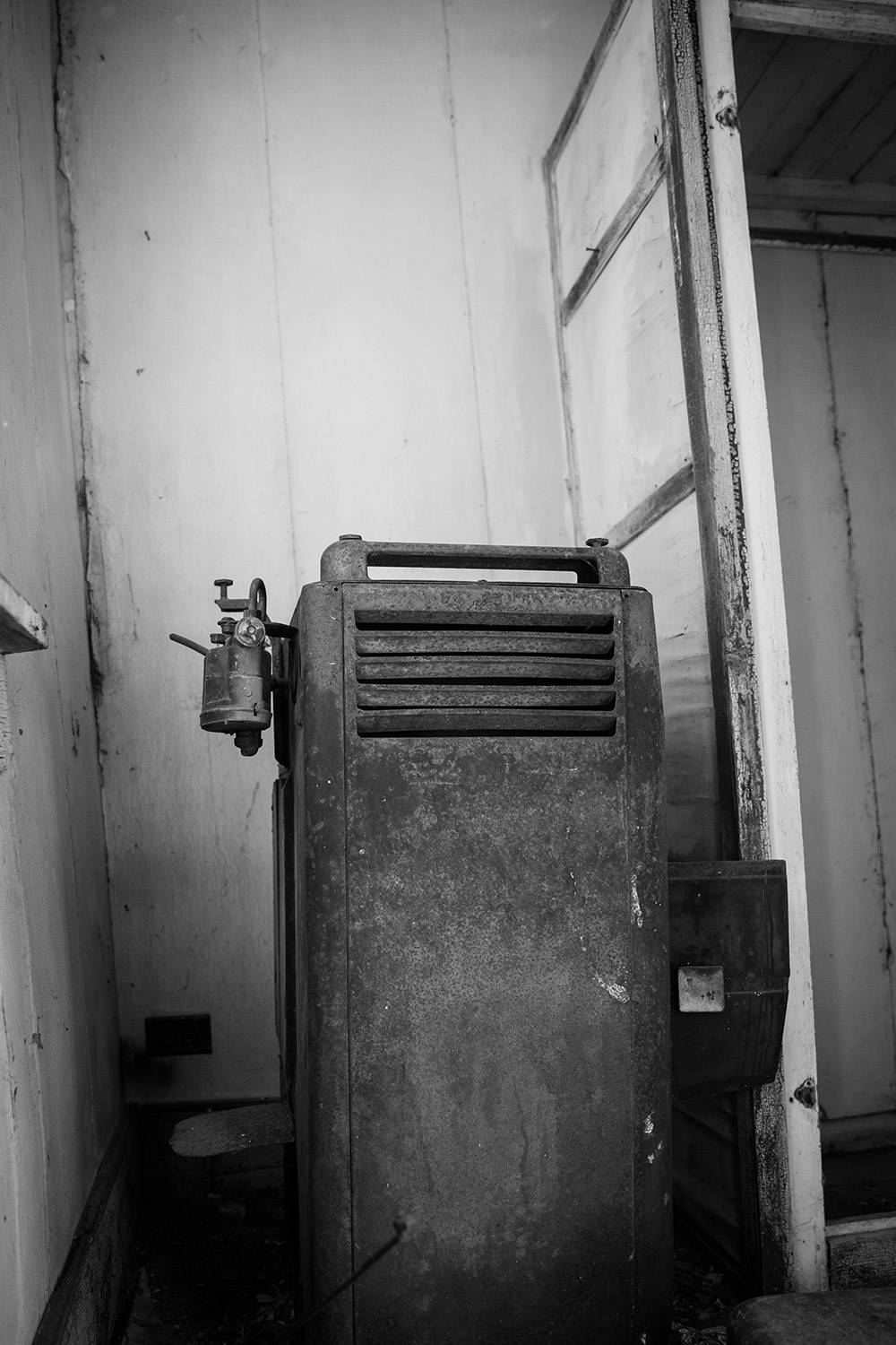 a black and white photo of an old appliance in an abandoned home