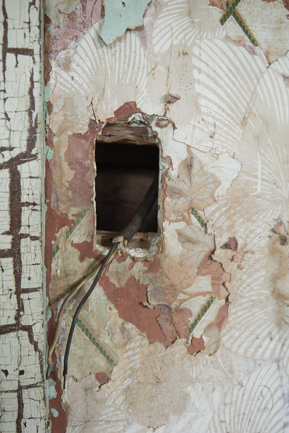 a photo of an old electrical socket surrounded by old layers of wallpaper