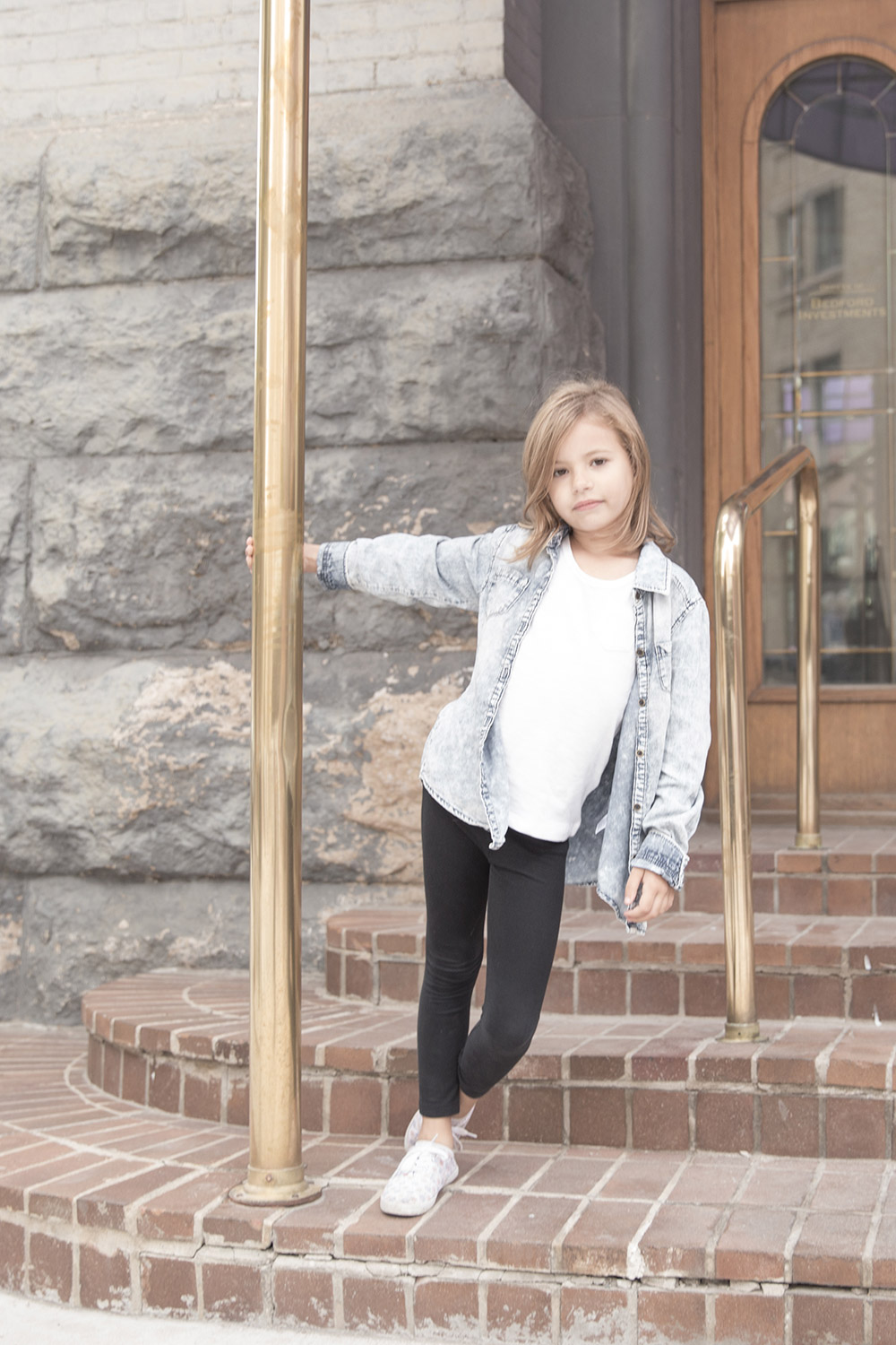 a photo of a young girl standing on stairs, holding a brass post