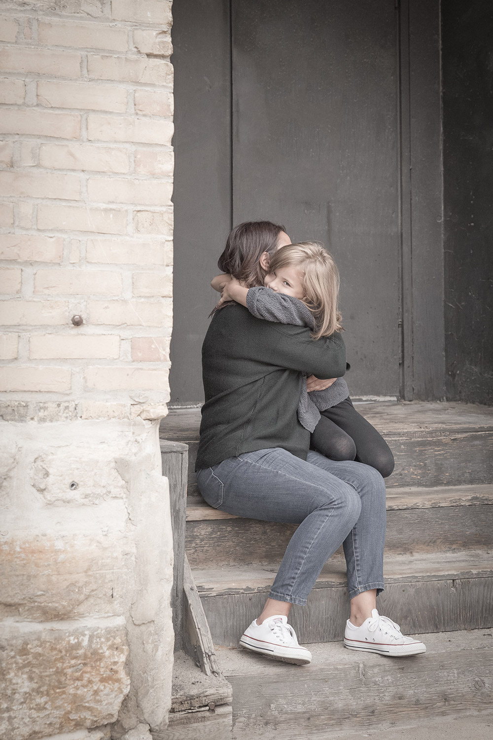 a photo of a mother and daughter hugging on concrete steps
