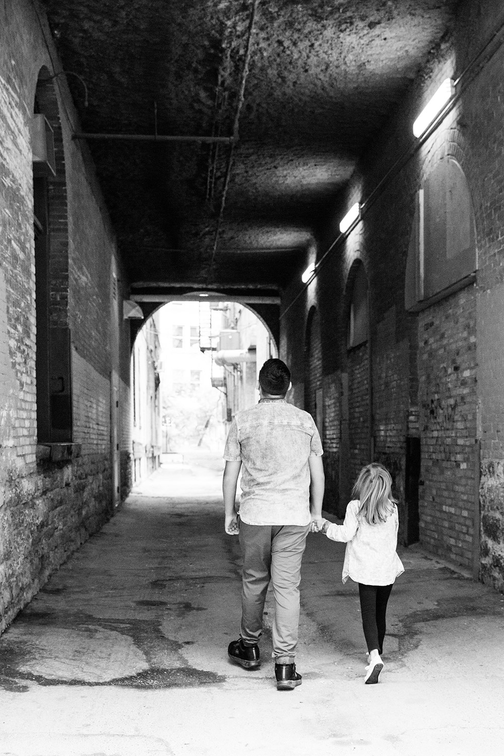 a photo of siblings walking through a tunnel holding hands