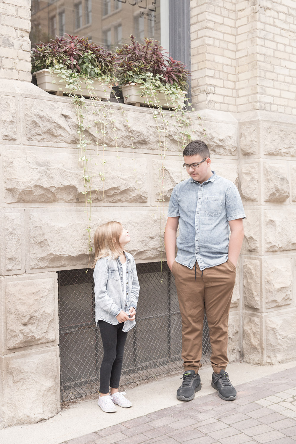 a photo of siblings standing together under a pretty wall