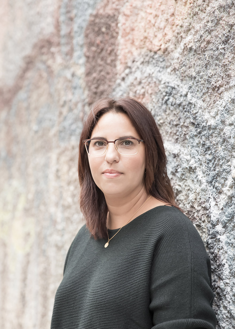 a portrait of a woman standing in front of a painted stucco wall