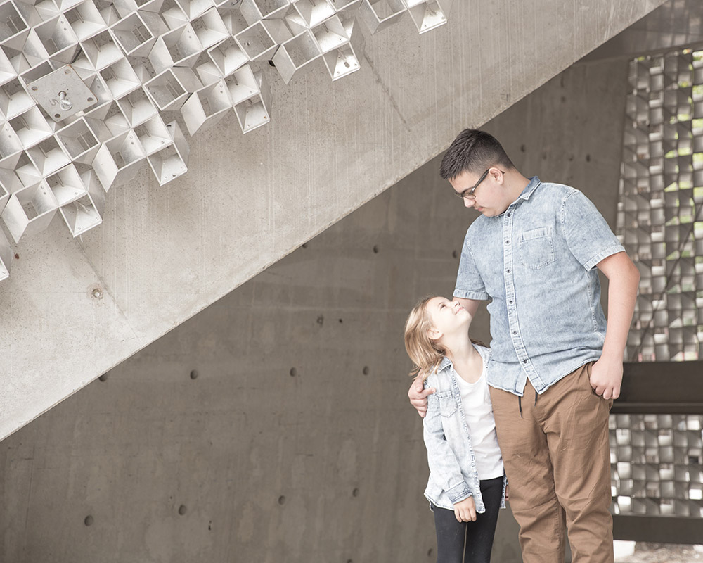 a photo of siblings looking at each other, framed with neat architecture