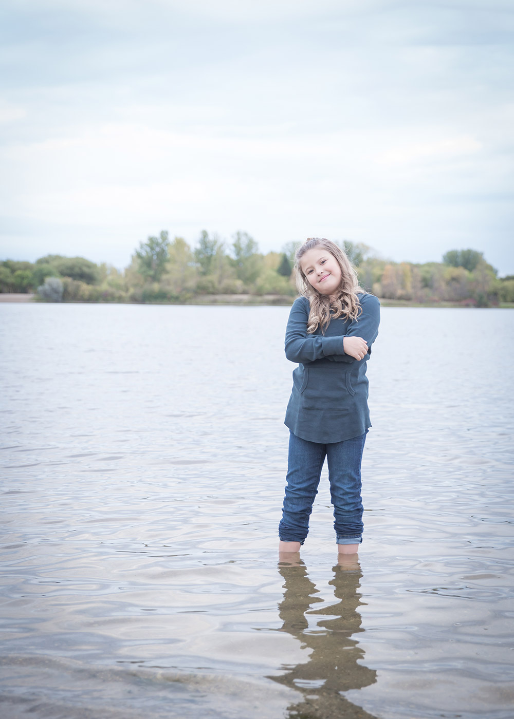 a photo of a young girl standing in a lake in the fall