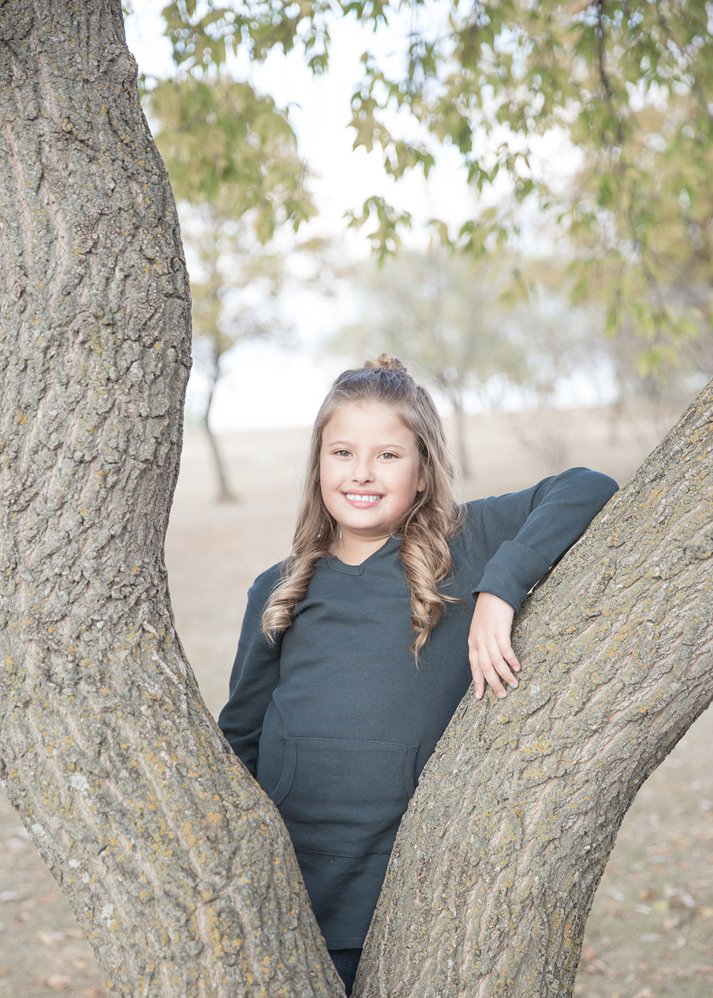 a photo of a young girl, posing with a large tree