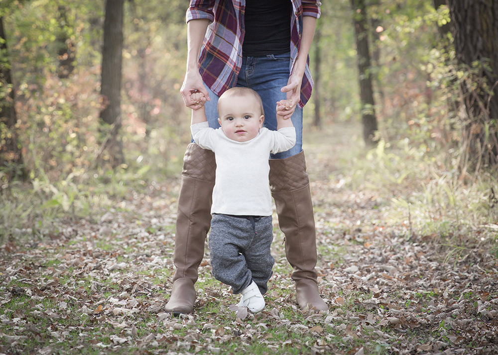 a photo of a baby boy walking with his mom holding his hands