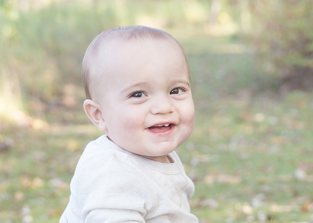 a photo of a smiling baby boy in the fall time outside
