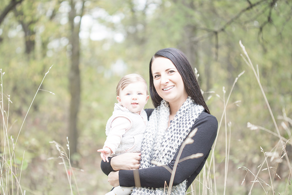 a photo of a mother and her baby girl standing in long grass in the fall