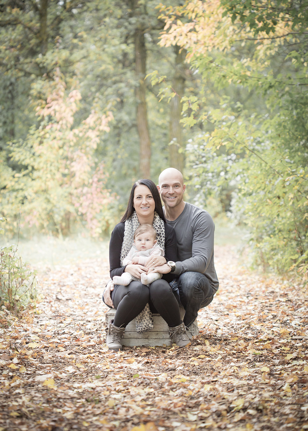 a photo of a young family surrounded by fall leaves