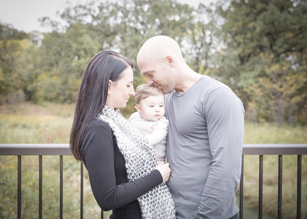 a photo of a young family standing on a bridge in the fall
