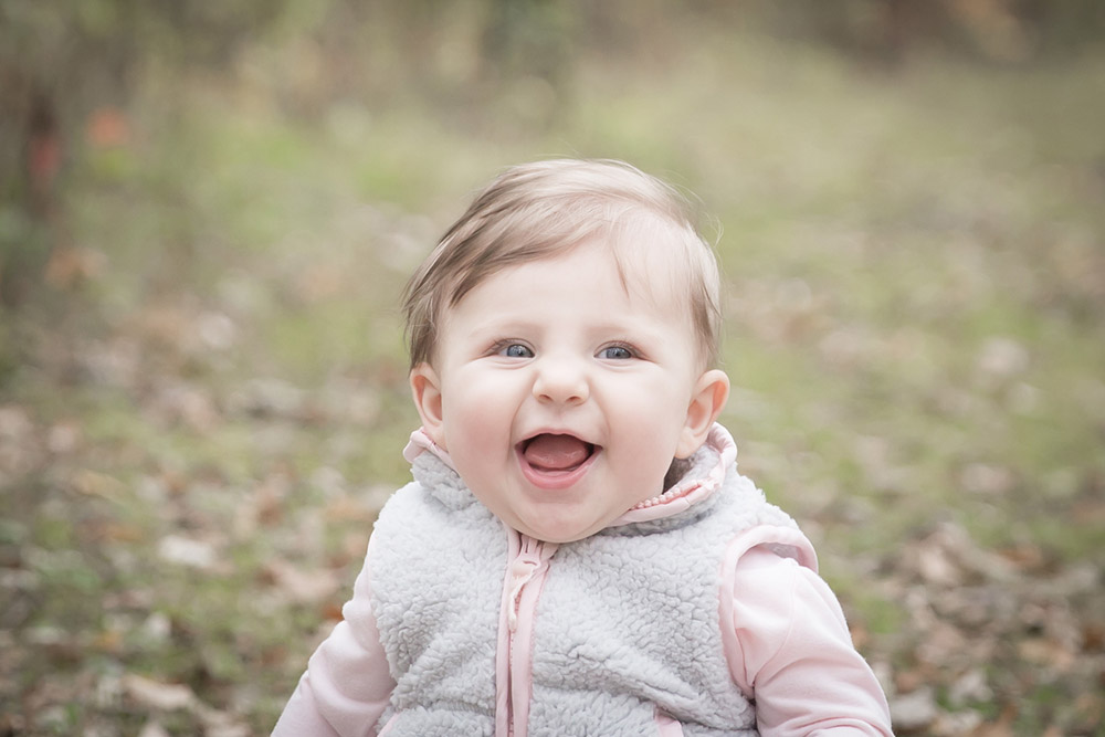 a photo of a happy baby girl sitting outside in the fall