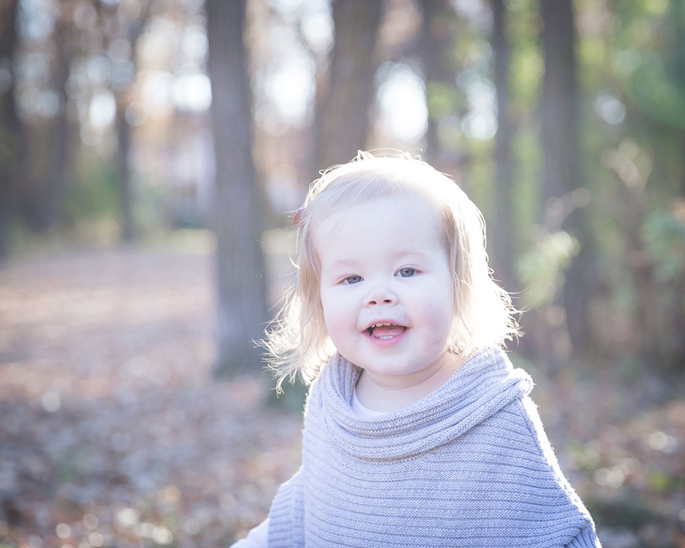 a photo of a happy little girl in the woods in fall