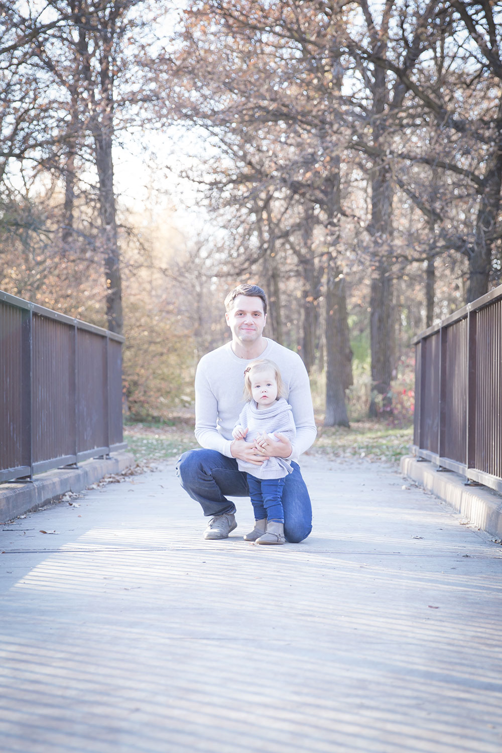 a photo of a father and daughter on a bridge in a park