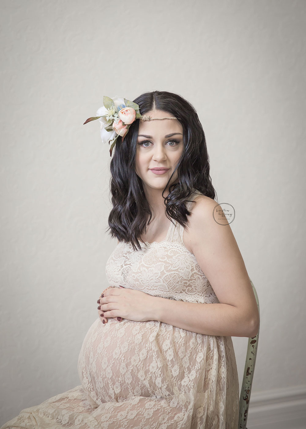 a maternity photo of a woman wearing a floral headpiece and a lace dress