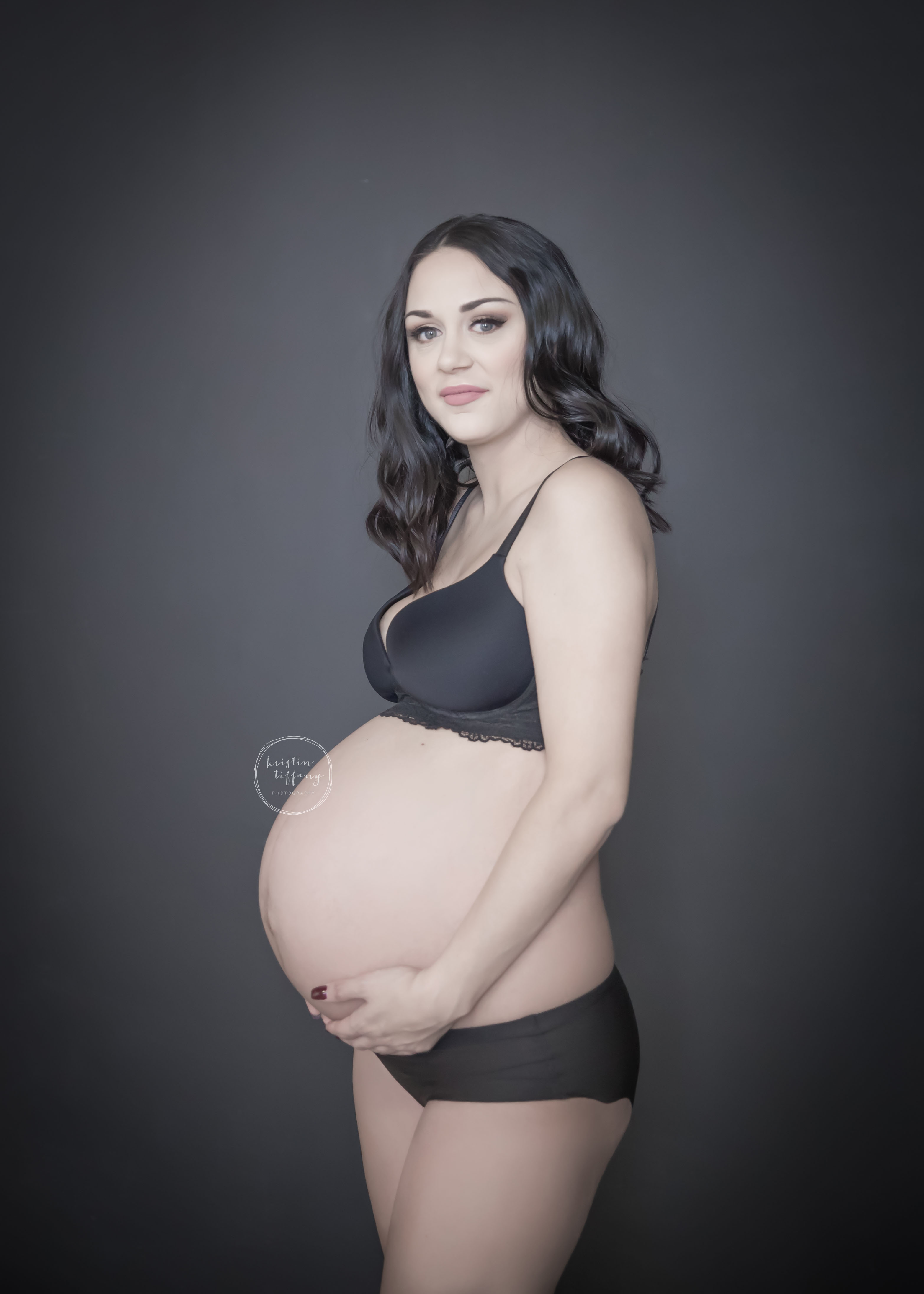 a maternity photo of a beautiful lady wearing black undergarnments