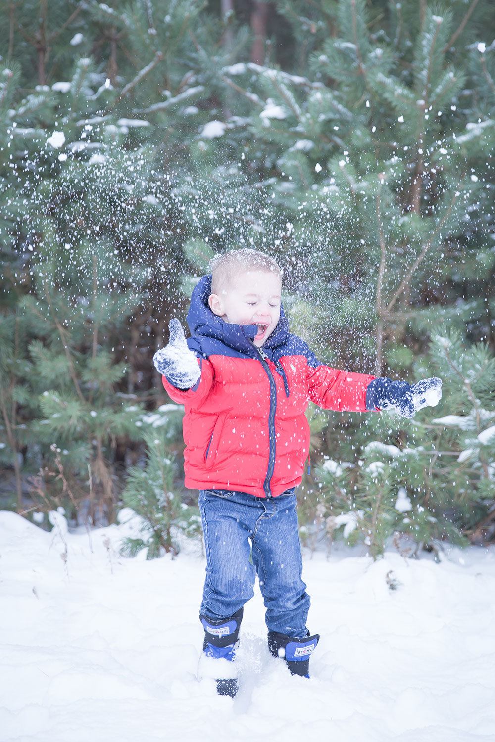a photo of a young boy throwing show into the air outside