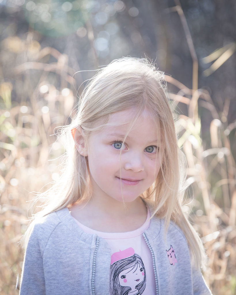 a photo of a young girl in the long grass in fall time