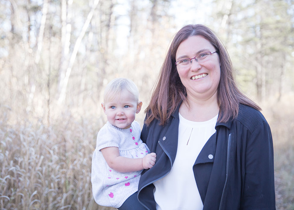 a photo of a mother holding her young daughter among long grass in fall
