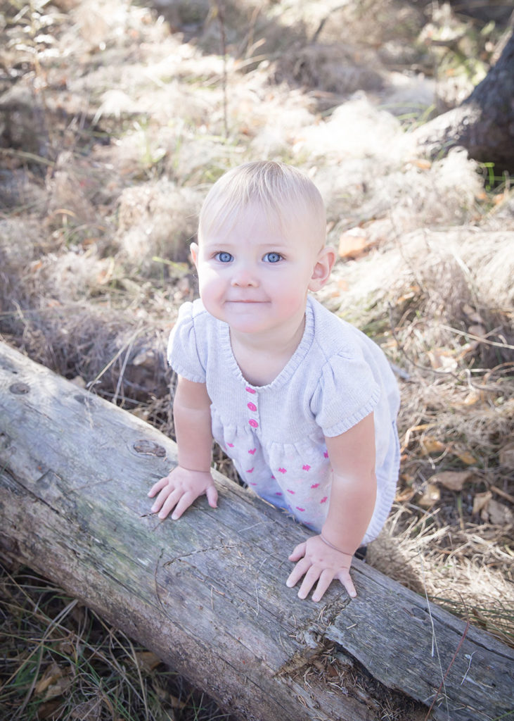 a photo of a little girl by a fallen tree in the woods