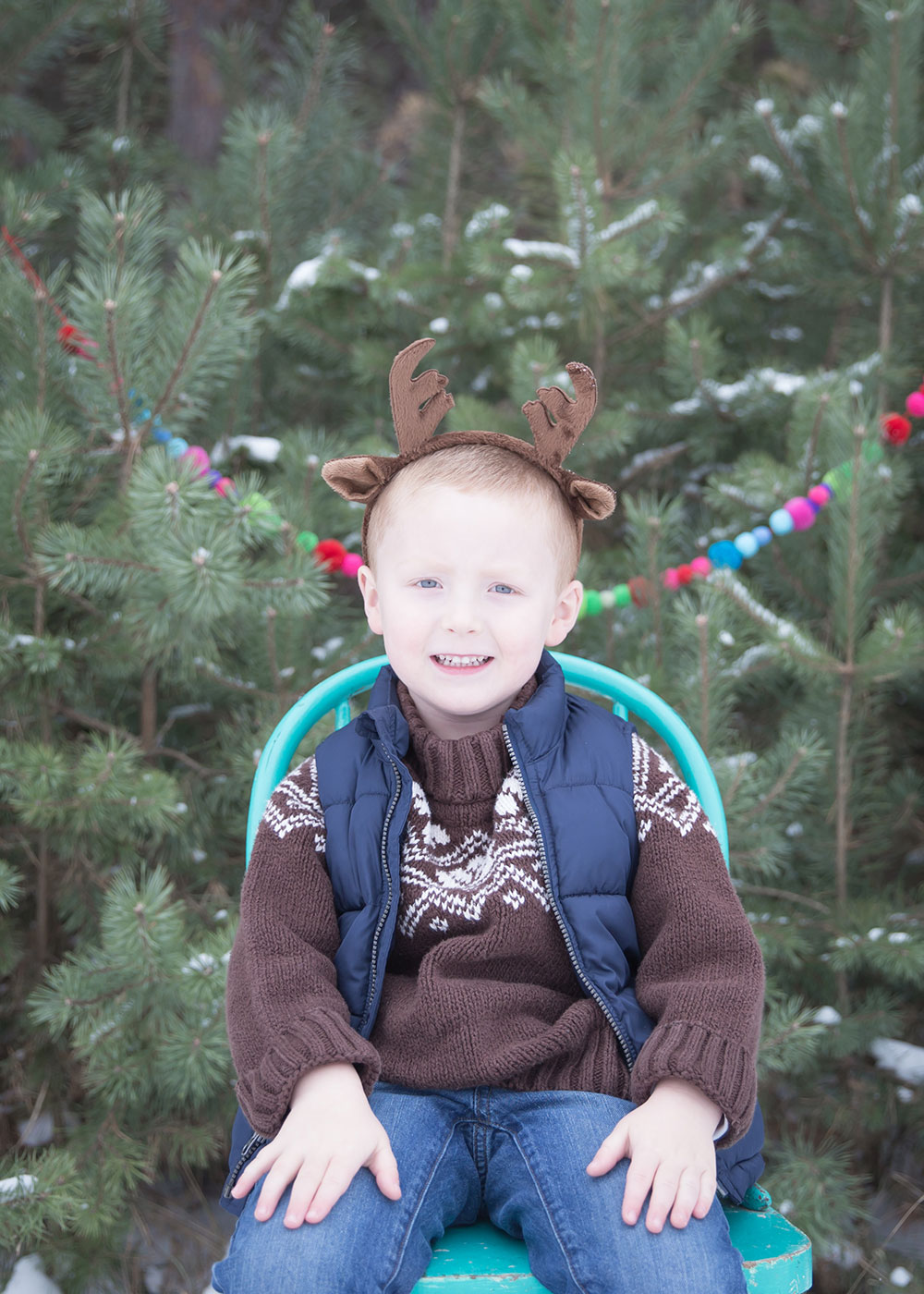 a photo of a young boy wearing reindeer antlers in the winter