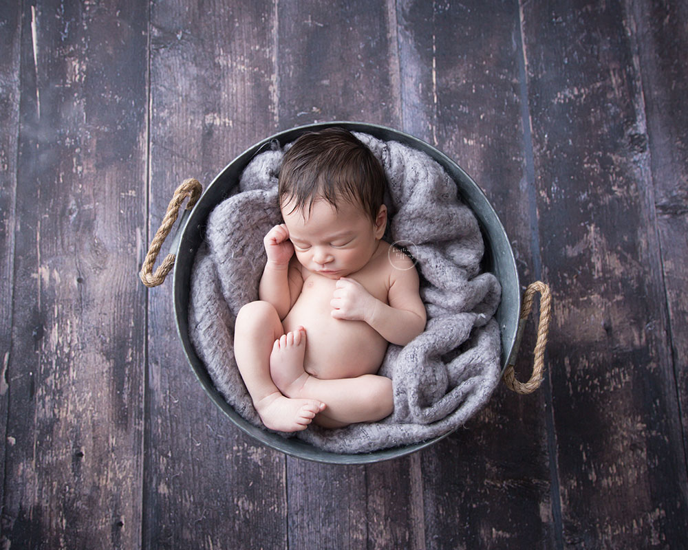 a photp of a newborn baby boy asleep in a metal basket