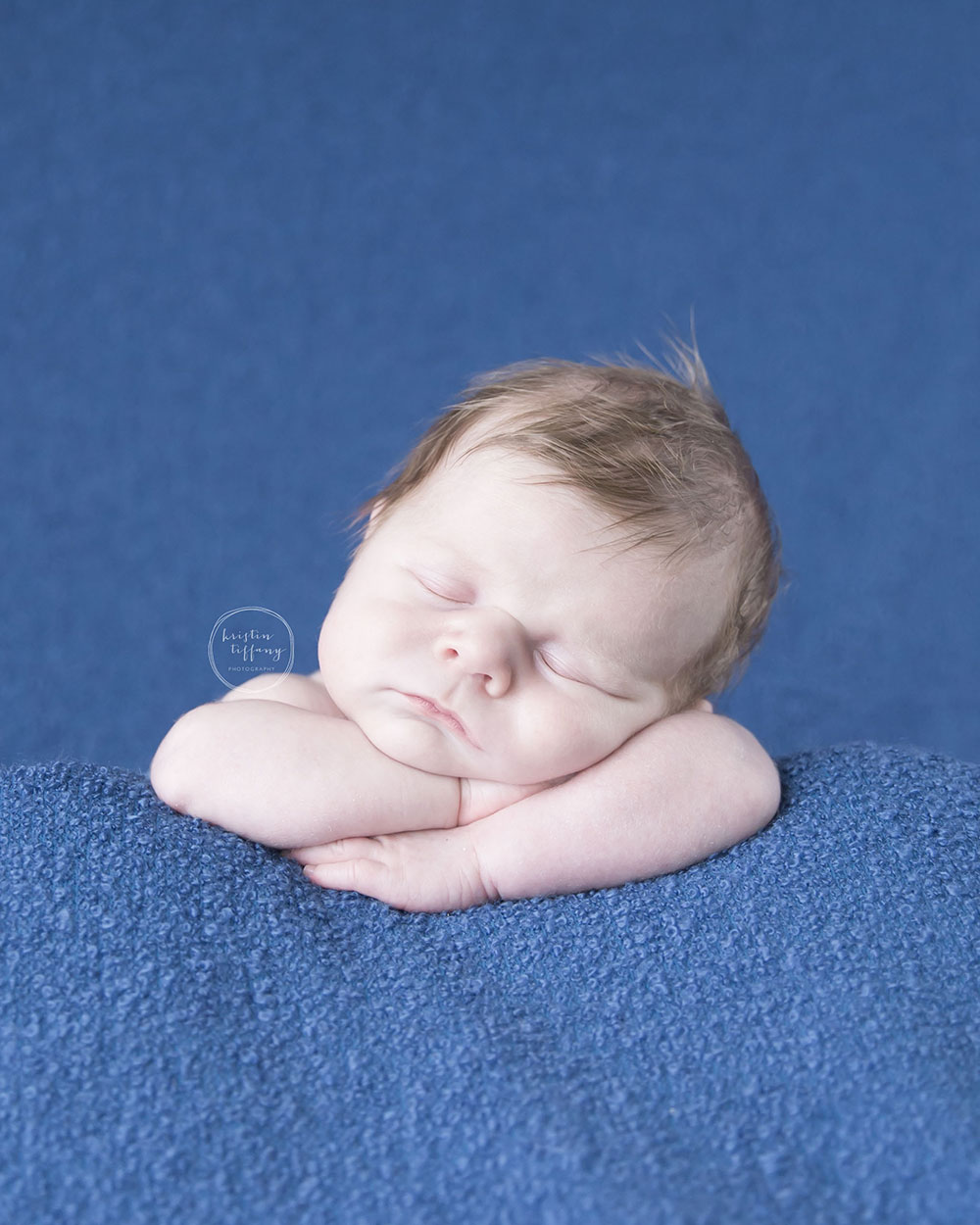 a newborn photo of baby boy posed with his head on his arms