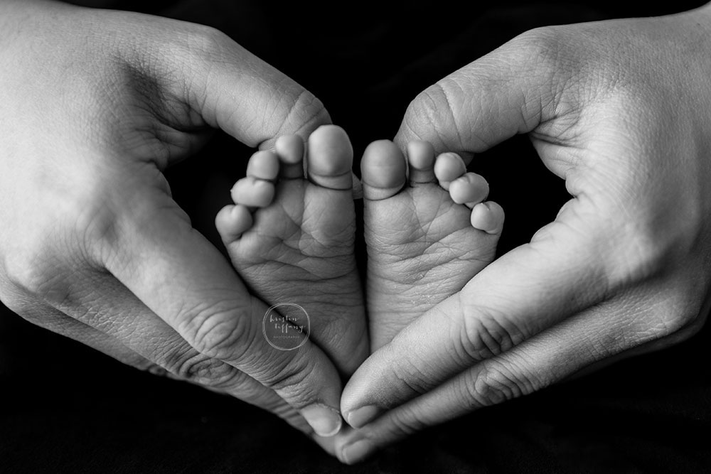 a photo of a mother holding her sons feet in a heart shape