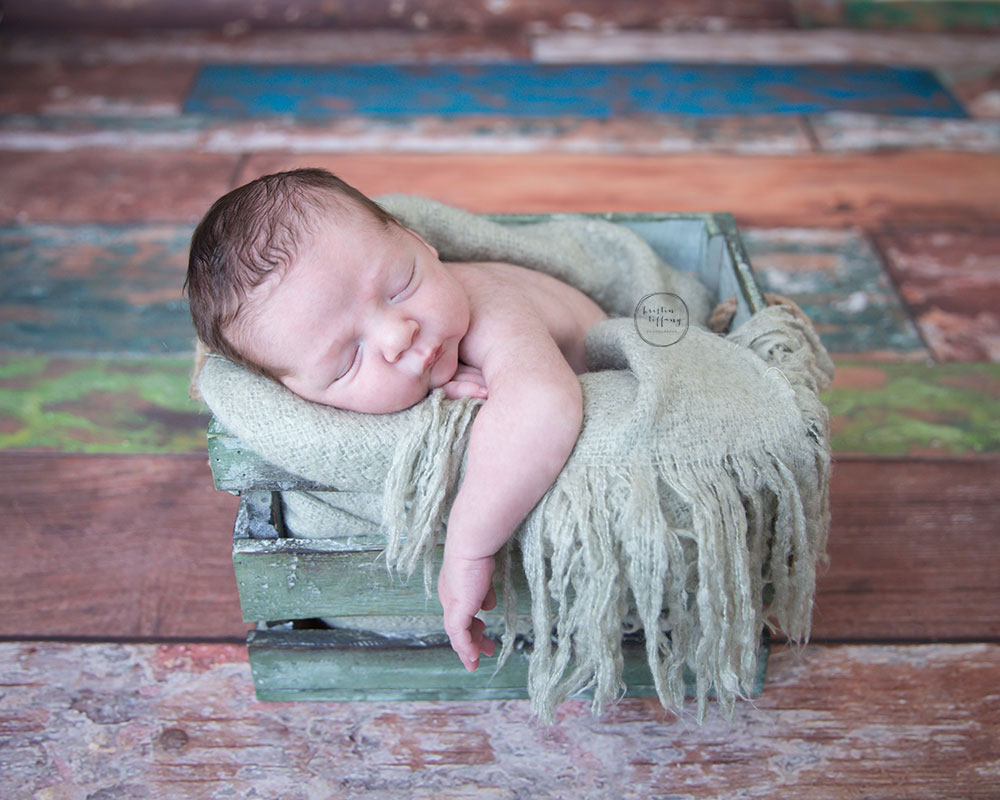 a photo of a newborn baby boy sleeping in a wooden crate