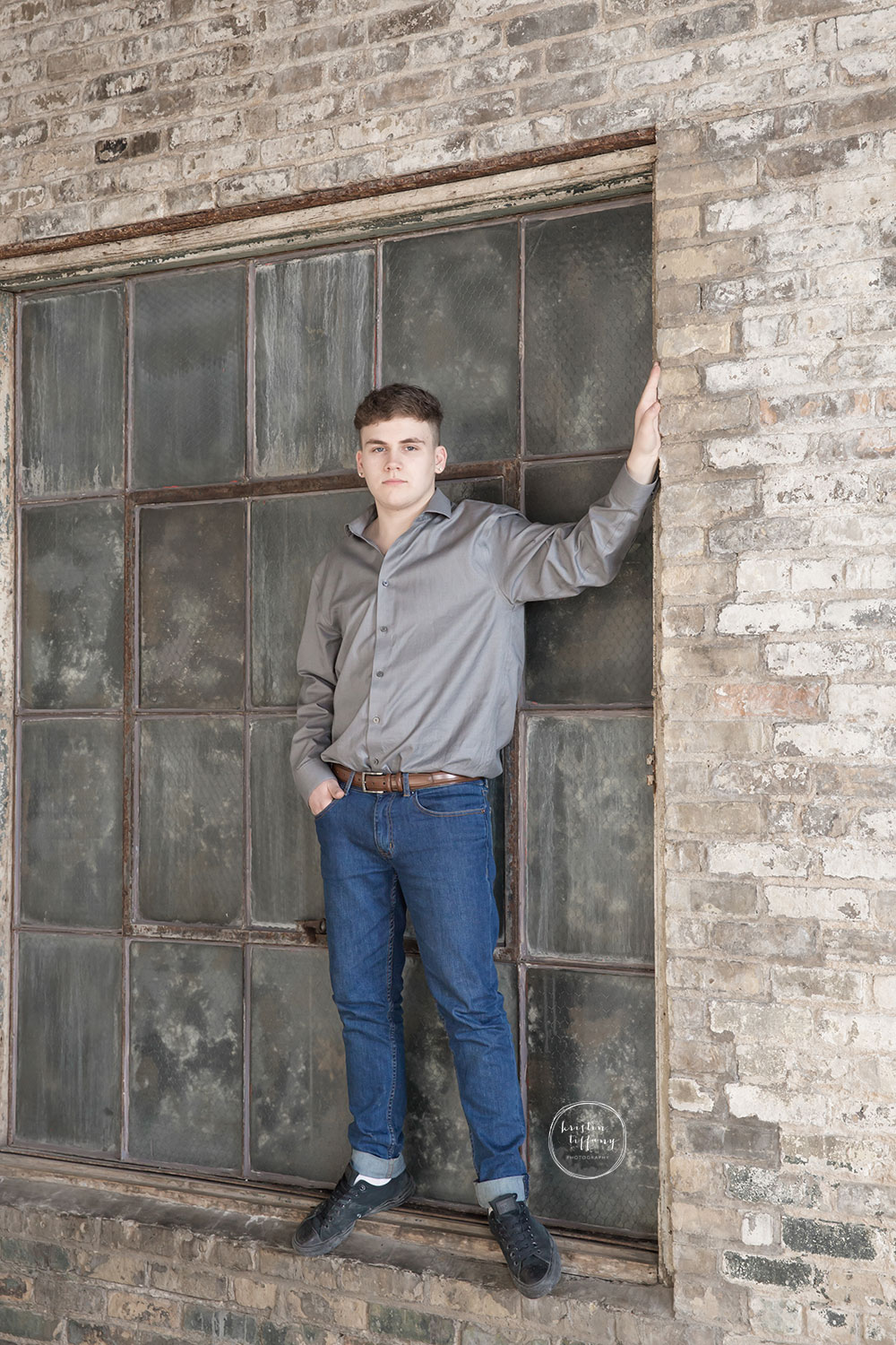 a photo of a young man standing in the window sill of an old window