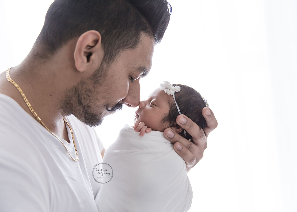a photo for a father holding is newborn daughter