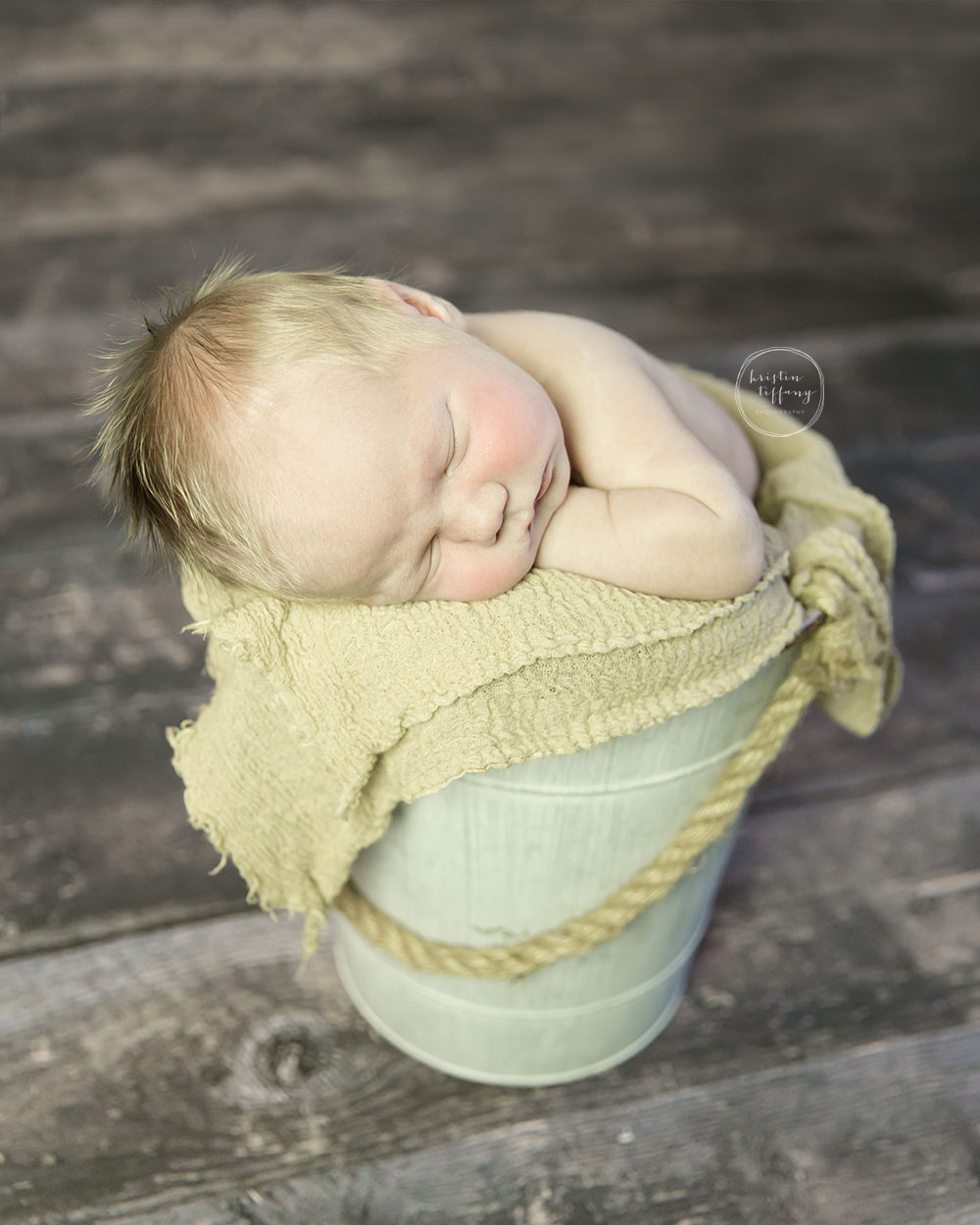 a photo of a posed sleeping baby boy in a metal bucket