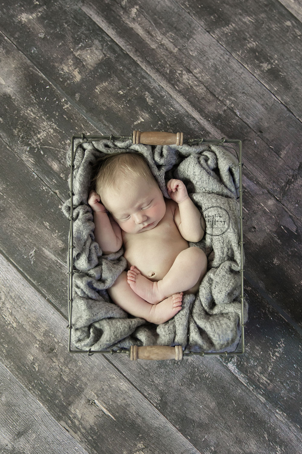 a photo of a posed sleeping baby boy in a wire basket