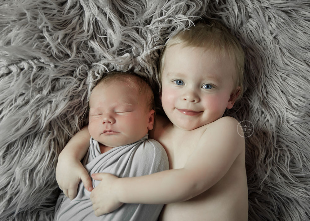 a photo of a posed sleeping baby boy and his big brother