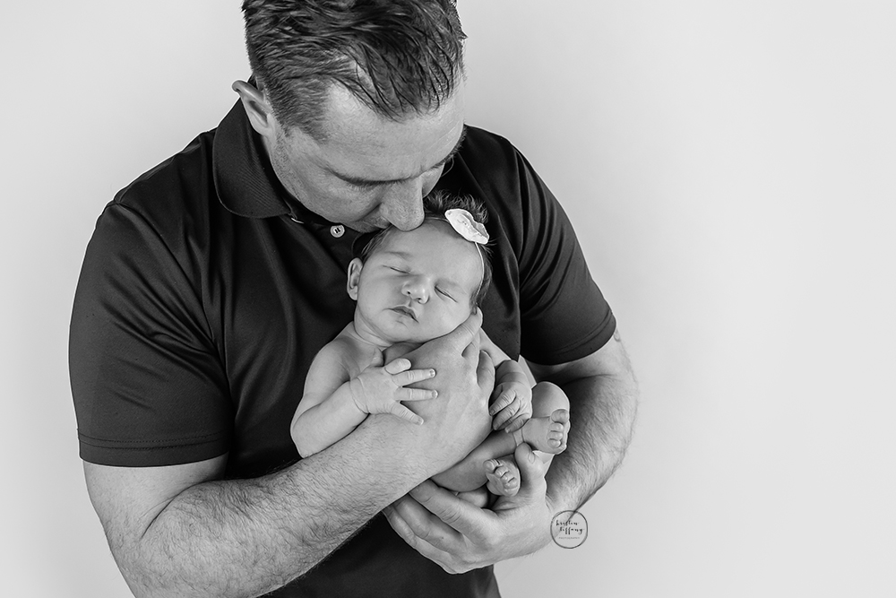 a photo of a newborn baby girl posed in her daddy's arms