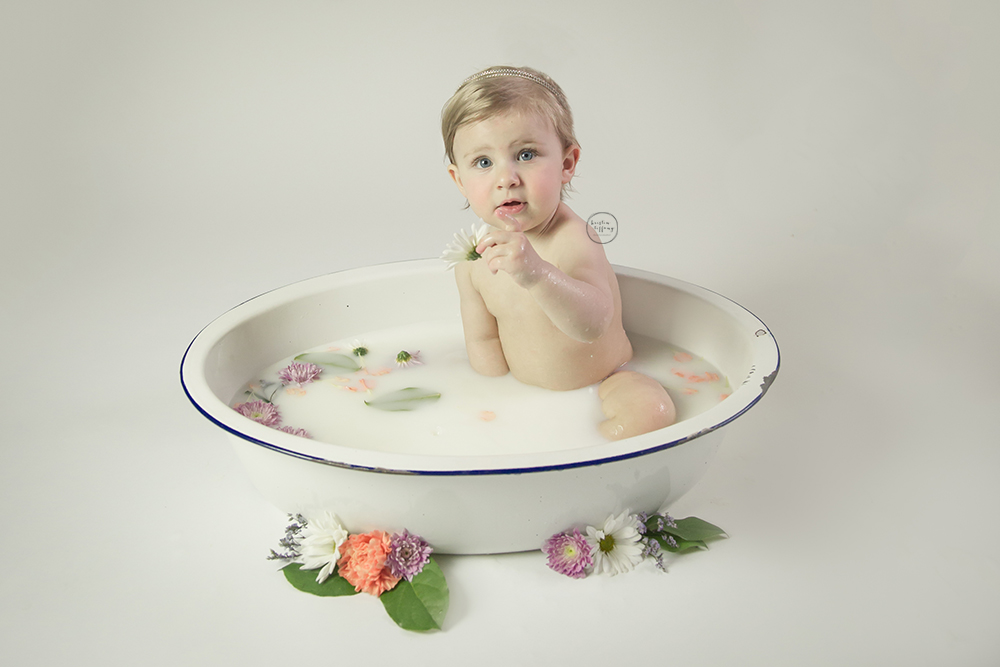 a photo of a baby girl having a floral milk bath