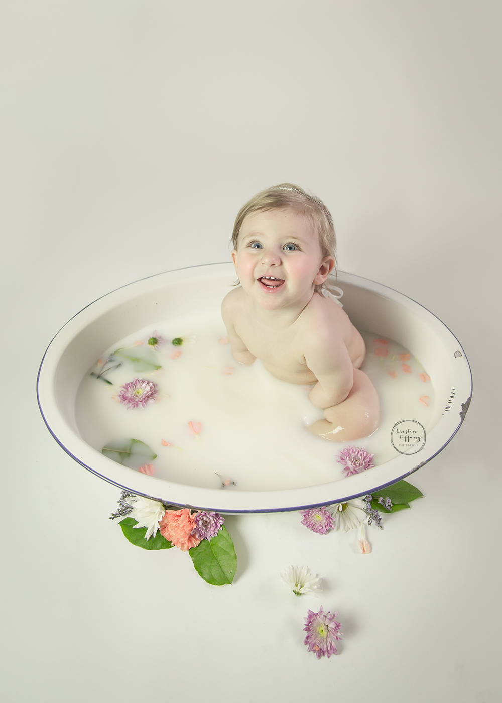 a photo of a baby girl in a floral milk bath