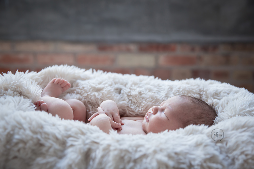 a photo of a newborn baby boy sleeping in a fur blanket