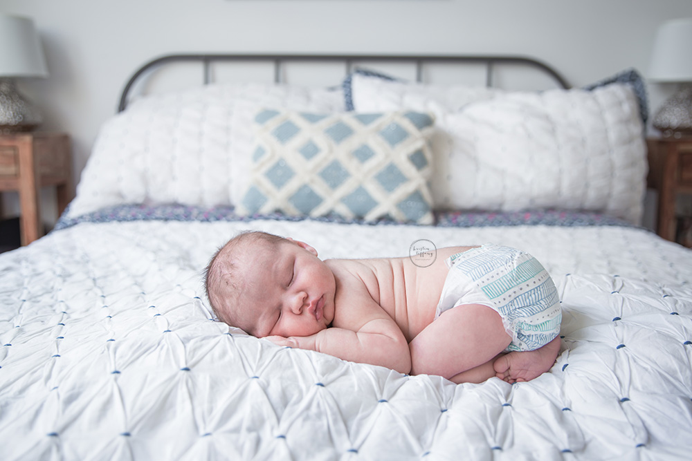 a photo of a newborn baby boy sleeping on his parents bed