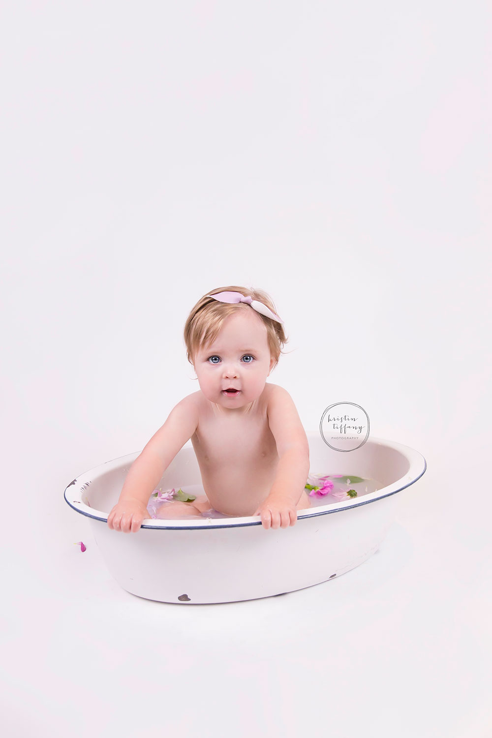 a photo of a baby girl in a floral milk bath