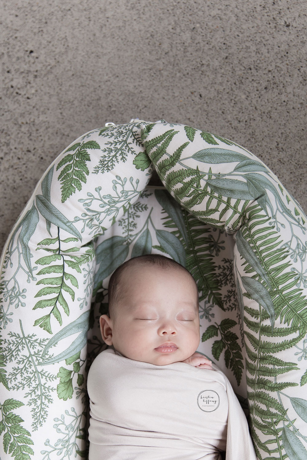 a photo of a baby boy in a leaf print baby bed