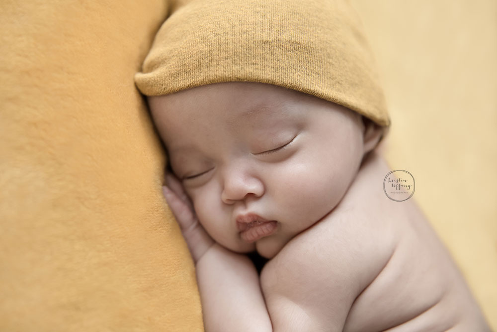 a photo of a baby boy sleeping in a yellow cap