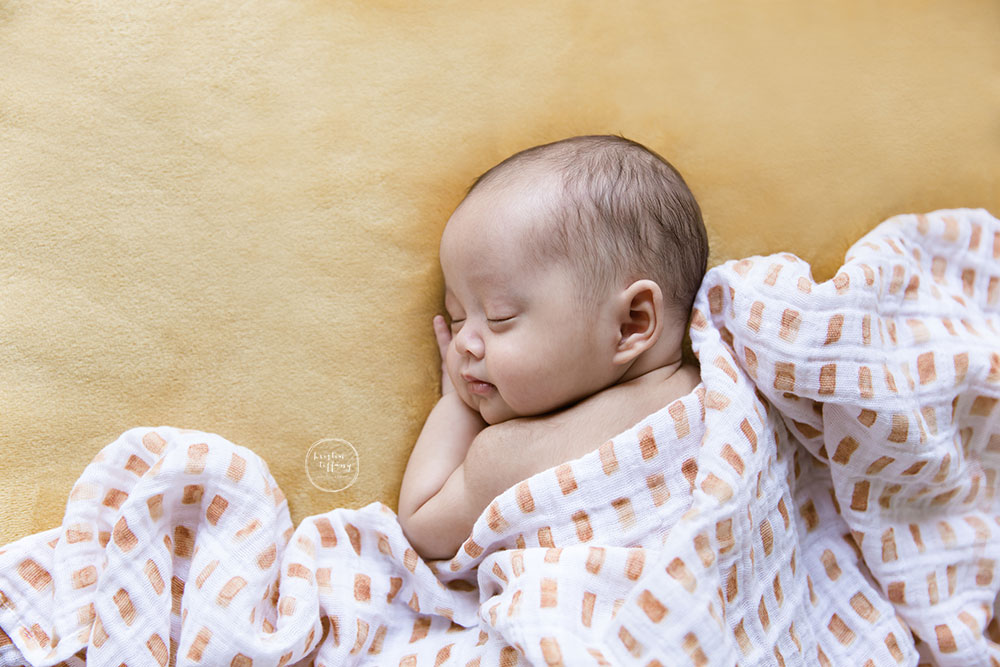 a photo of a baby boy sleeping on a yellow blanket