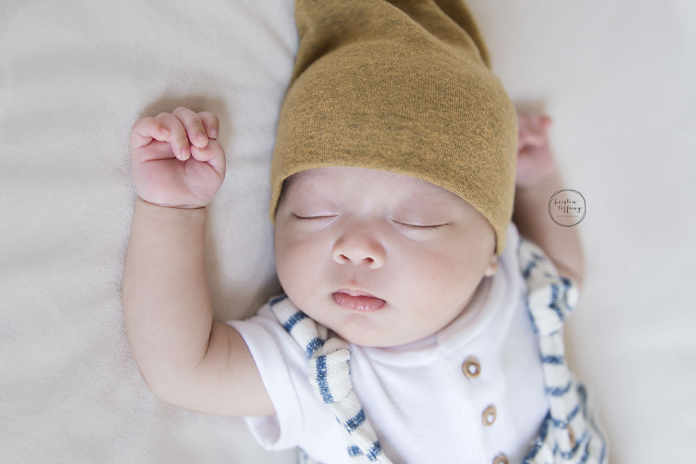 a photo of a baby boy sleeping in a yellow hat and striped romper