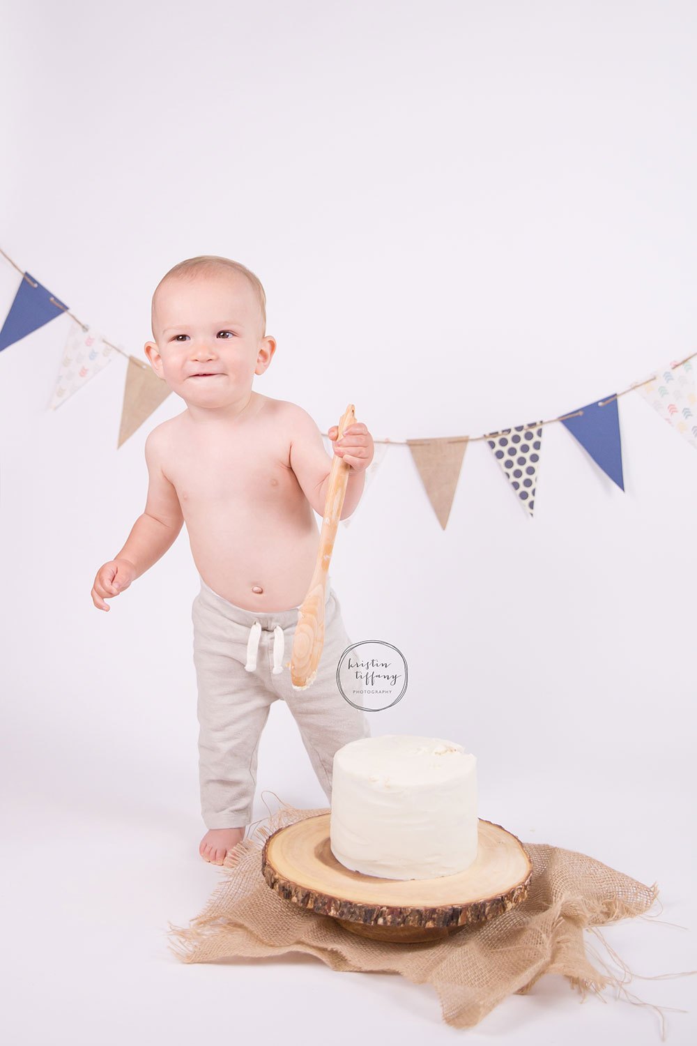 a photo of a baby boy with a cake smash cake and wooden spoon