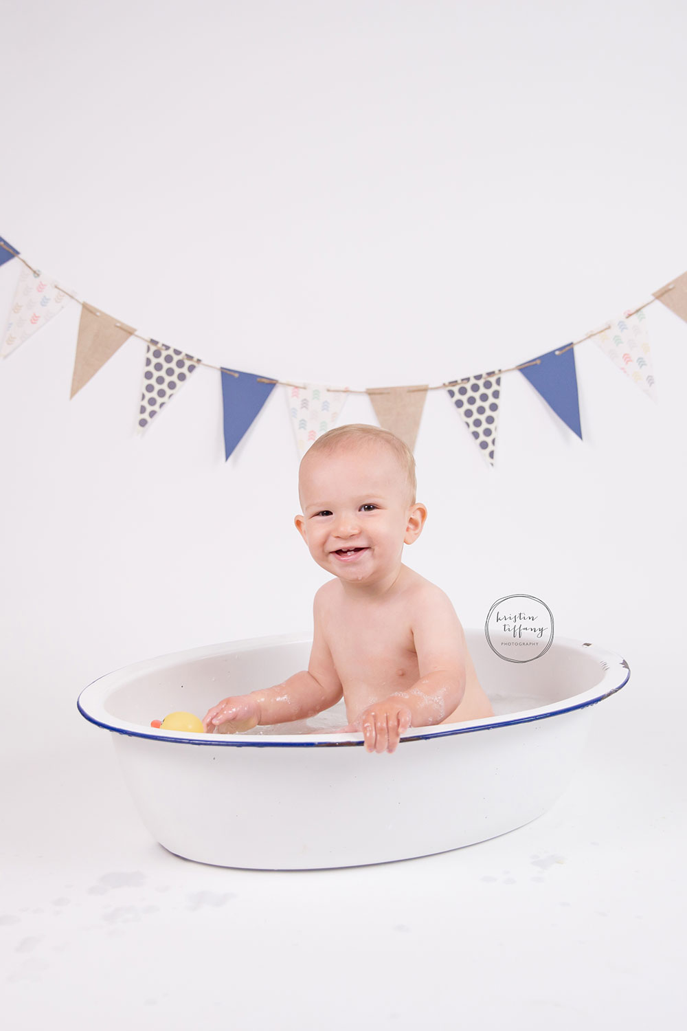 a photo of a baby boy having a bubble bath in an old wash basin